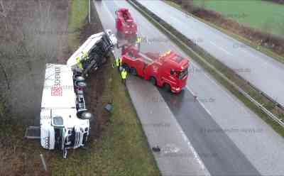 Lastzug mit Reinigungsmitteln kommt von Autobahn ab und kippt auf die Seite: Gefahrgutzug der Feuerwehr im Einsatz: Zugfahrzeug und Anhänger umgekippt - Feuerwehrleute in Schutzanzügen entladen Lastzug - Lange Behinderungen auf der A21 für Bergung erwartet